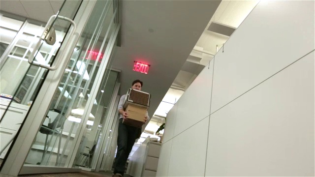 被解雇的员工沮丧地沿着办公室走廊走向装有行李的摄像机(荷兰，摄影车拍摄)视频下载