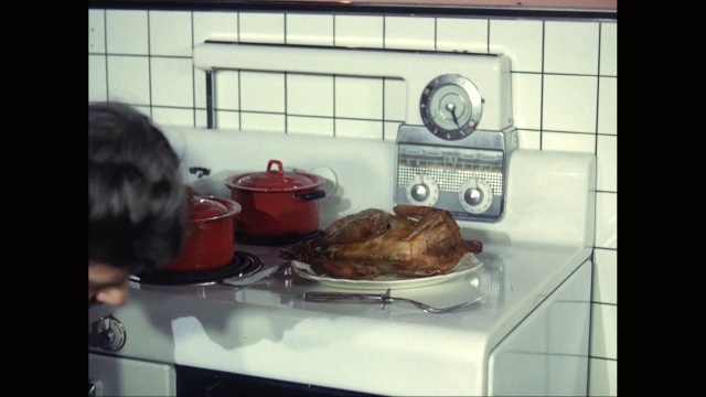 在美国，一名妇女正在从家庭厨房的烤箱中取出鸡肉视频下载