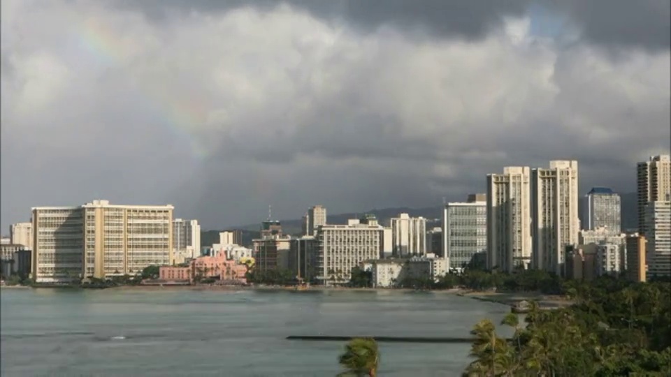 彩虹断断续续地出现在暴风雨的沿海城市附近。视频素材