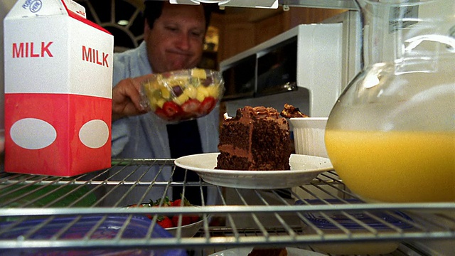 冰箱的视点人打开门，举起一块巧克力蛋糕，却拿着一碗水果视频下载