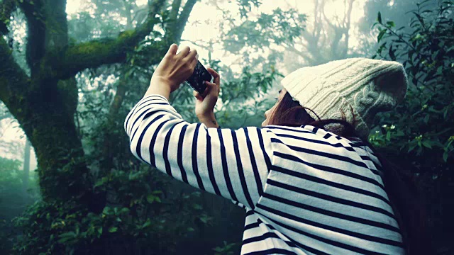 台湾阳明山，一名年轻女子正在用智能手机拍摄雾霾森林的全景照片视频下载