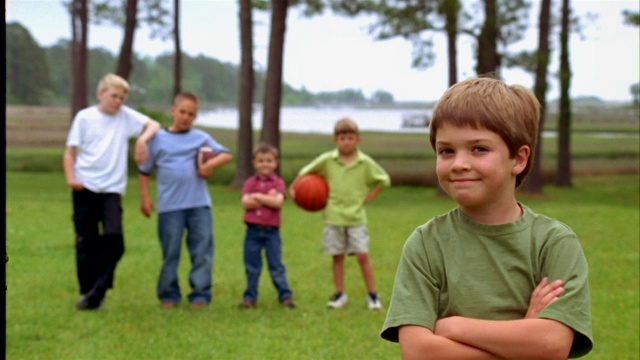 一个小男孩双臂交叉站在他的一群朋友面前。视频下载