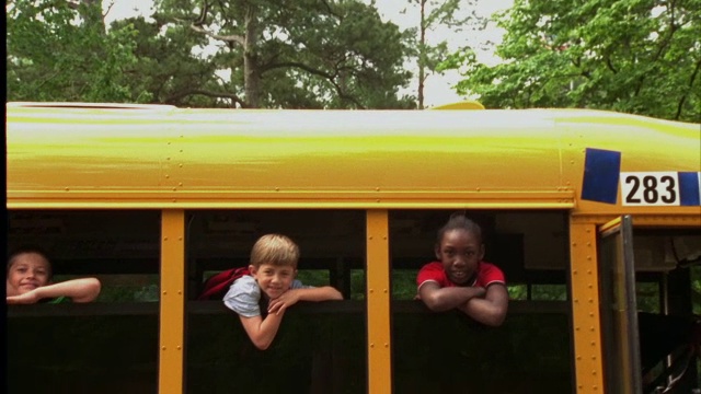 孩子们从一辆校车的窗户探出头来。视频素材