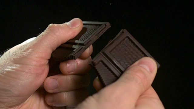一个人掰开黑巧克力的近距离镜头。视频素材