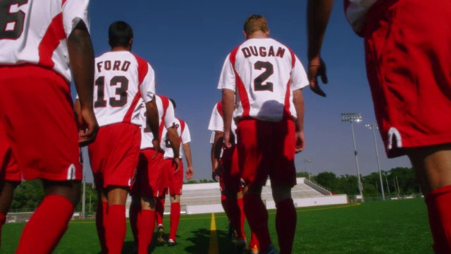 一群足球运动员沿着足球场的边线一起走。视频素材
