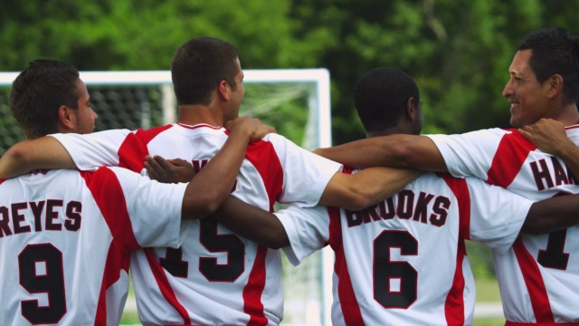 一队足球运动员站在一起，双臂交叉放在对方的肩膀上。视频素材