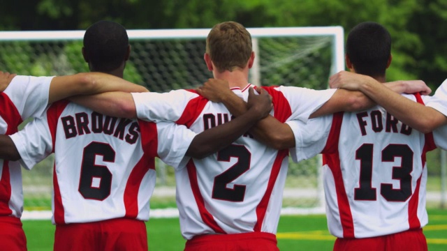 足球运动员站成一排，手臂搭在对方的肩膀上。视频下载