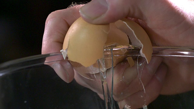 一颗鸡蛋被玻璃碗打碎的慢镜头。视频素材