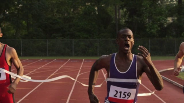 一名赛跑运动员冲过终点线，并在比赛中战胜了他的竞争对手。视频素材