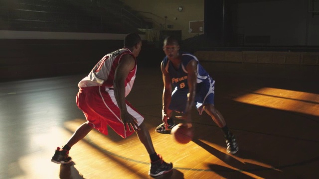 篮球运动员在一对一比赛中绕着防守队员运球。视频下载