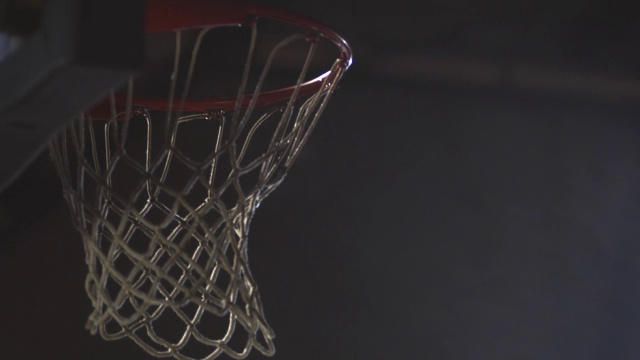 当一个篮球穿过网时，一个聚光灯照亮了体育馆。视频下载