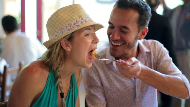 在巴西餐馆里，一名男子让女友吃一口自己的食物视频素材