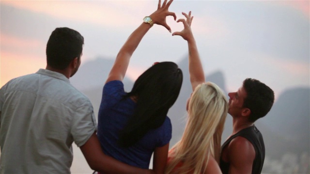 日落时分，依帕内玛的海滩上，朋友们手拉手制作心形视频素材