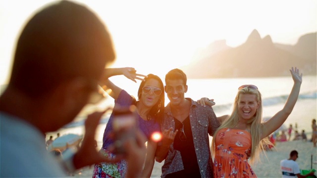 日落时分，朋友们在依帕内玛海滩上用智能手机拍照视频素材
