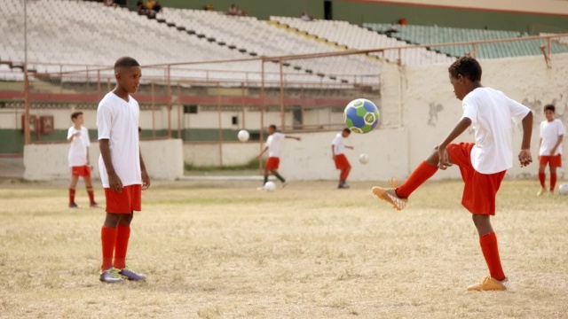 巴西男孩在旧体育场的训练场上来回踢足球视频素材
