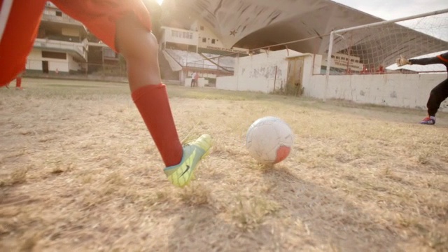 年轻的足球运动员在场上运球，并在守门员的双手之间踢球得分视频素材