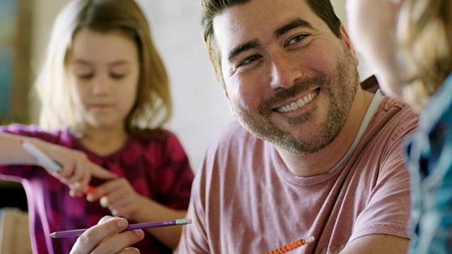 微笑的父亲帮助孩子放学后做作业。视频素材
