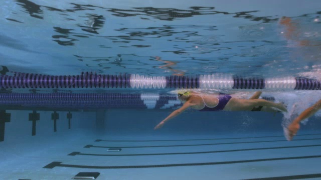游泳运动员参加自由泳比赛，当他们到达泳池壁时在水下转身。视频素材