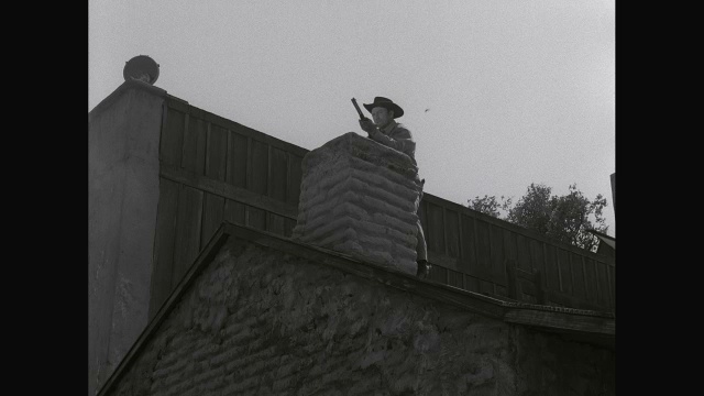 牛仔在附近的烟囱上打磨，在屋顶上用散弹枪射击视频素材
