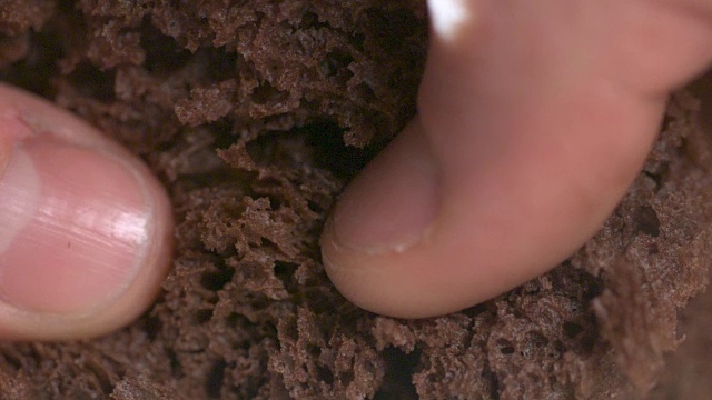 一个人掰开巧克力蛋糕的慢镜头近景。视频素材