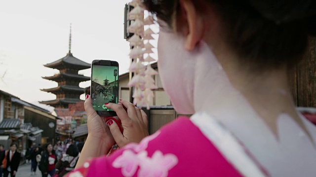 日本京都，一名打扮成舞妓的女子在电话上拍照视频素材
