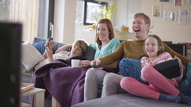 一家人坐在沙发上笑着看电视视频素材