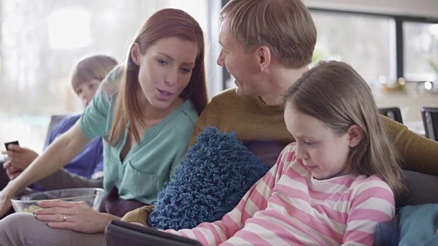 父亲和女儿在沙发上玩平板电脑视频素材