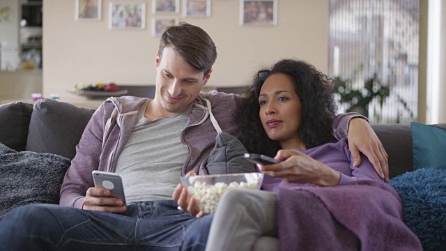 DS男一边和女朋友看电视一边玩手机视频素材