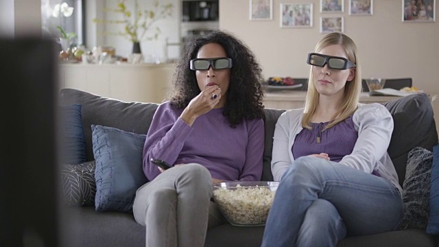 两个女人一边吃爆米花一边看3D电视视频素材