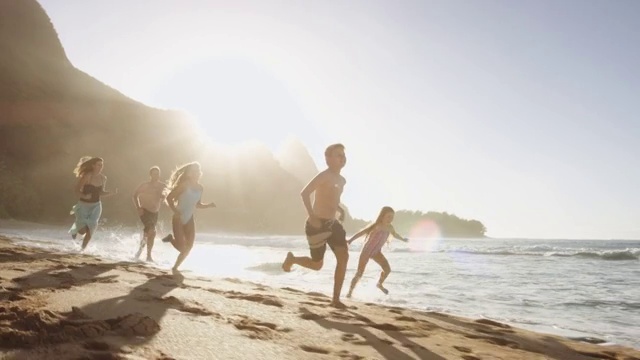 小男孩在海滩上奔跑，家人跟在后面视频素材