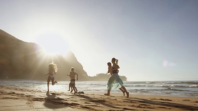 一个白人家庭在海滩上奔跑视频素材
