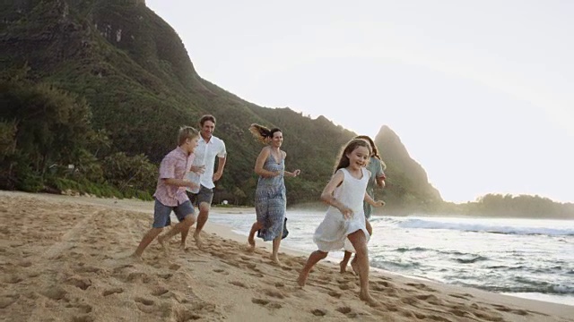 一个白人家庭在日落时沿着海滩玩耍视频素材