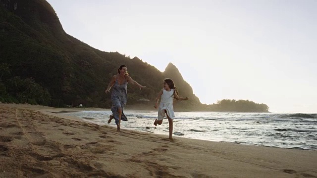 母亲和小女儿在海滩上奔跑视频素材