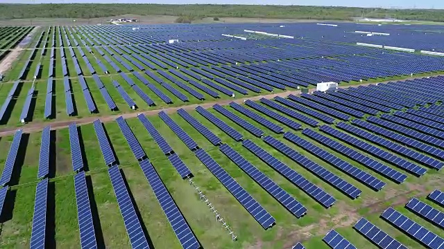 无尽的太阳能电池板无人机俯瞰大规模太阳能农场附近的奥斯汀，美国德克萨斯州，绿草和蓝色面板反射长版本完美的角度视频素材