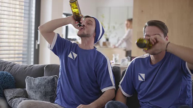 两个男性朋友一边看足球比赛一边欢呼视频素材