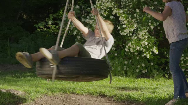 中等平移的女孩旋转男孩的轮胎秋千/斯普林维尔，犹他州，美国视频素材