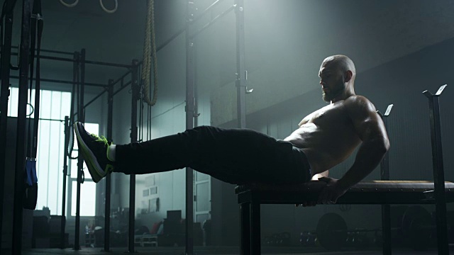 男人在长凳上做仰卧起坐，锻炼他的腹肌视频素材