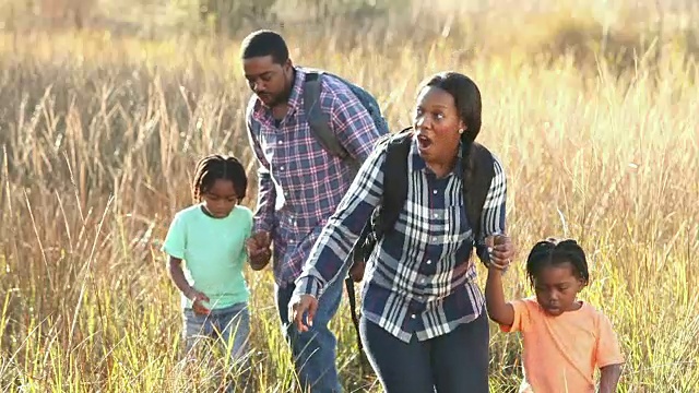 一个非裔美国家庭带着两个小男孩徒步旅行视频素材