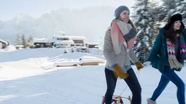两个年轻的女人拉着雪橇视频素材