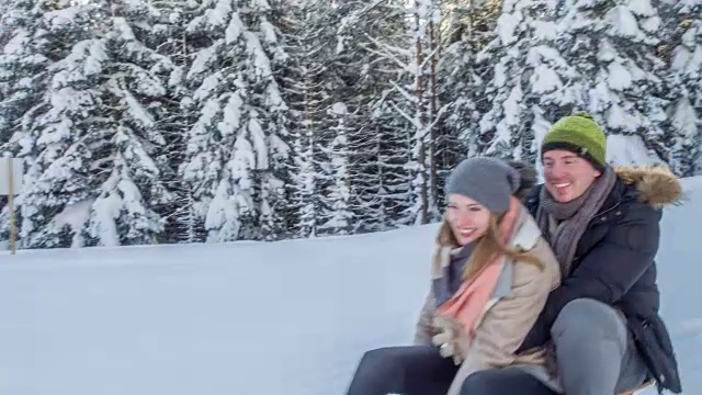 年轻夫妇在雪地上玩雪橇视频素材