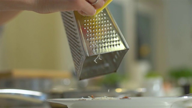 用金属刨丝器把黄色奶酪磨碎，慢动作视频下载