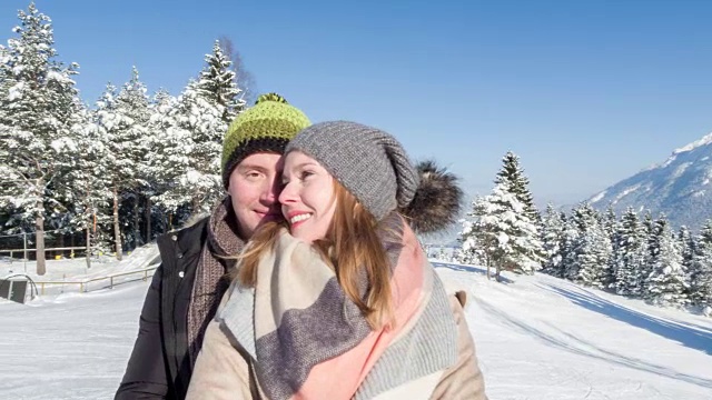 在巴伐利亚阿尔卑斯山脉的冬季风景中，一对年轻夫妇拥抱在一起视频素材
