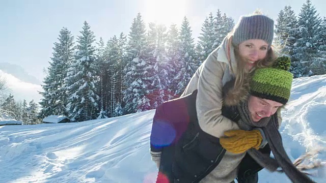 在冬天的景色中，一个年轻人让他的女朋友骑在他的背上视频素材