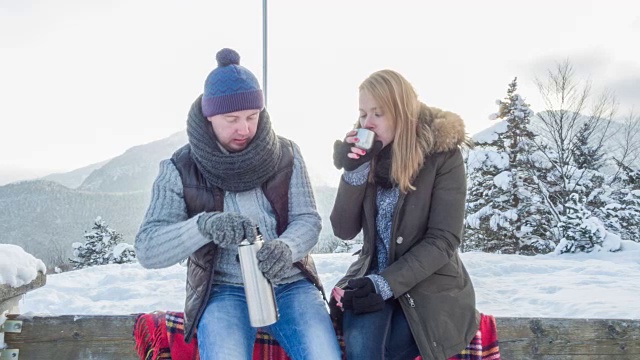 年轻夫妇在雪山中休息，喝着热茶视频下载