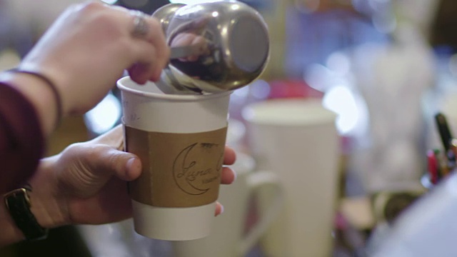 铜。当地咖啡店的咖啡师将意式浓缩咖啡倒入加味的卡布奇诺中。视频素材