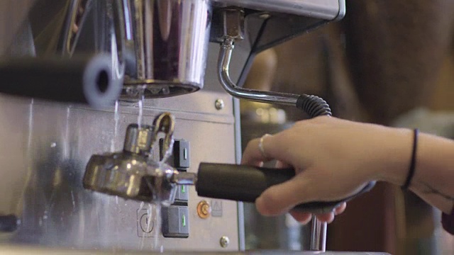 铜。在现代咖啡店里，咖啡师冲洗浓缩咖啡机的过滤网。视频素材
