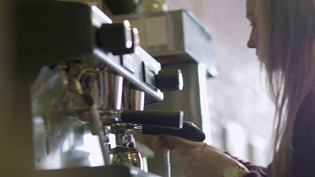 在现代咖啡店里，咖啡师调整了设置，开始使用浓缩咖啡机。视频素材