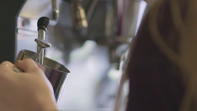 铜。现代咖啡店里的咖啡师用浓缩咖啡机的蒸汽棒使牛奶起泡。视频素材
