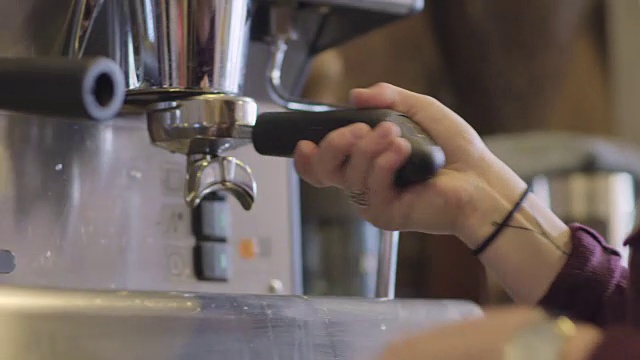 铜。熟练的咖啡店员工用捣碎机快速地将咖啡压碎，并将咖啡渣放入咖啡机中。视频素材