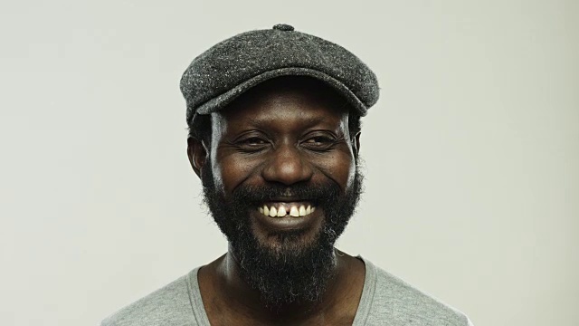 一个成熟的非洲男人笑着，看着远处灰色的背景视频素材